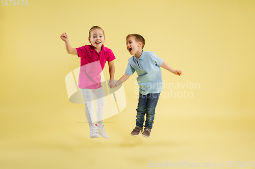 Image of Childhood and dream about big and famous future. Pretty little kids isolated on yellow studio background