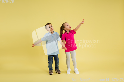 Image of Childhood and dream about big and famous future. Pretty little kids isolated on yellow studio background