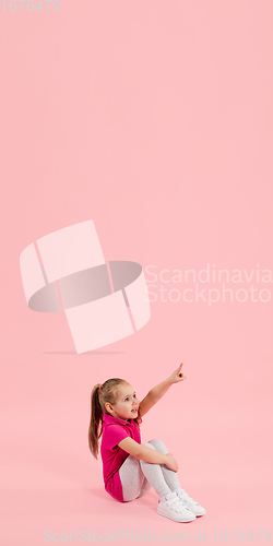 Image of Childhood and dream about big and famous future. Pretty little girl isolated on coral pink background