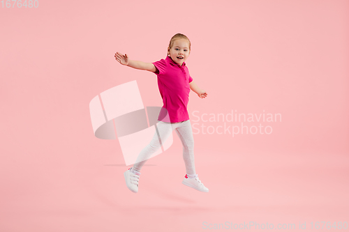 Image of Childhood and dream about big and famous future. Pretty little girl isolated on coral pink background