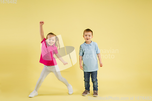 Image of Childhood and dream about big and famous future. Pretty little kids isolated on yellow studio background