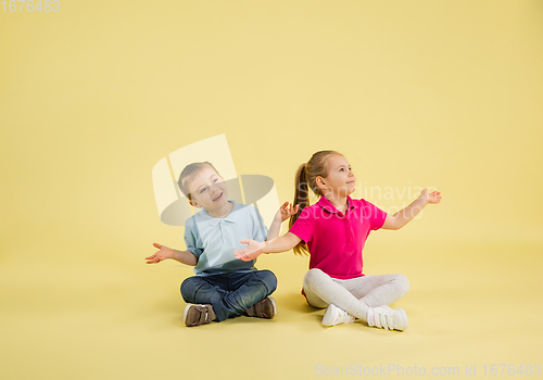 Image of Childhood and dream about big and famous future. Pretty little kids isolated on yellow studio background