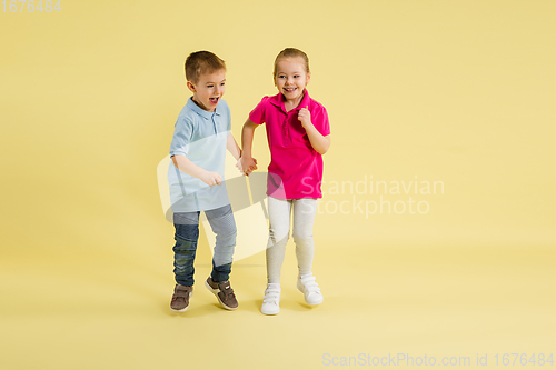 Image of Childhood and dream about big and famous future. Pretty little kids isolated on yellow studio background