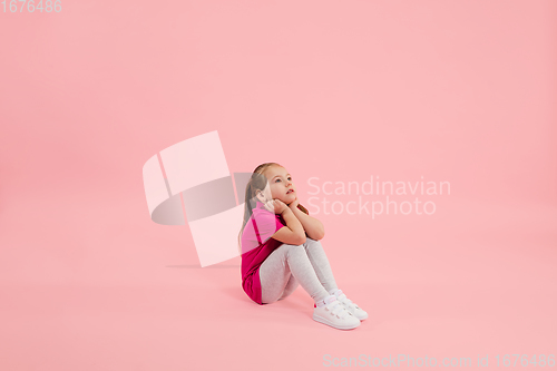 Image of Childhood and dream about big and famous future. Pretty little girl isolated on coral pink background