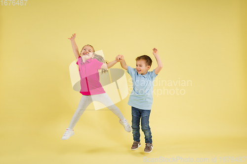 Image of Childhood and dream about big and famous future. Pretty little kids isolated on yellow studio background