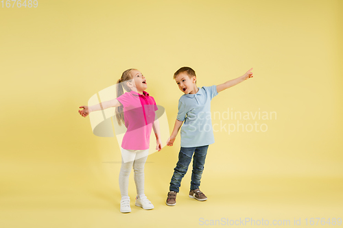 Image of Childhood and dream about big and famous future. Pretty little kids isolated on yellow studio background