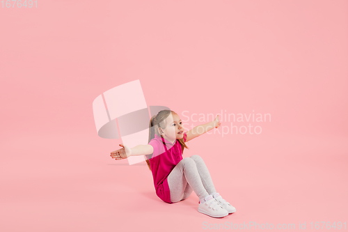 Image of Childhood and dream about big and famous future. Pretty little girl isolated on coral pink background