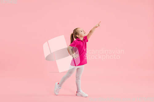 Image of Childhood and dream about big and famous future. Pretty little girl isolated on coral pink background