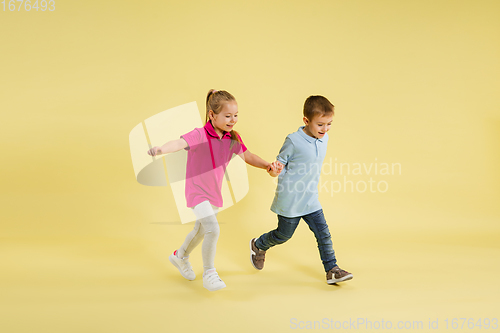 Image of Childhood and dream about big and famous future. Pretty little kids isolated on yellow studio background