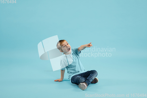 Image of Childhood and dream about big and famous future. Pretty little boy isolated on blue background