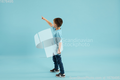 Image of Childhood and dream about big and famous future. Pretty little boy isolated on blue background