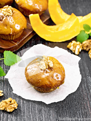 Image of Cupcake pumpkin with orange glaze and walnuts on black board