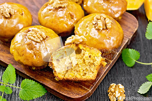 Image of Cupcake pumpkin with orange glaze and walnuts on brown board