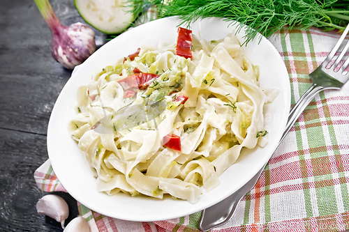 Image of Fettuccine with zucchini and hot peppers in plate on black woode