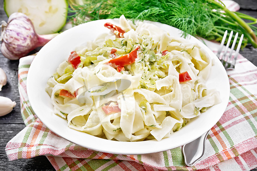 Image of Fettuccine with zucchini and hot peppers in plate on wooden boar