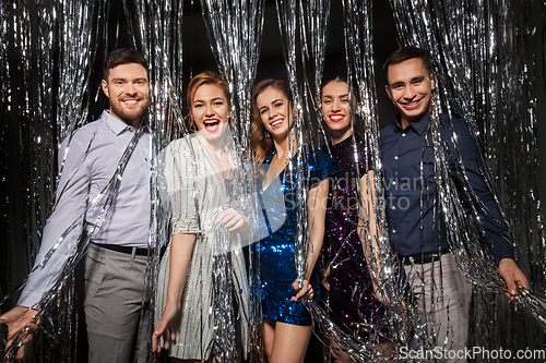 Image of happy friends in party clothes with tinsel curtain