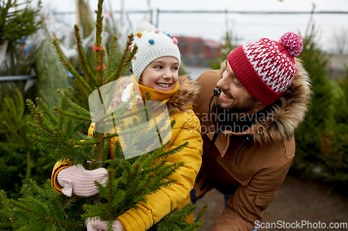 Image of happy family choosing christmas tree at market