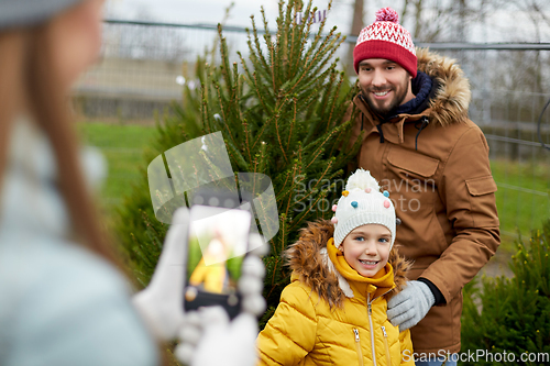 Image of family taking picture of christmas tree at market