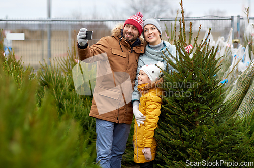 Image of family taking selfie with christmas tree at market