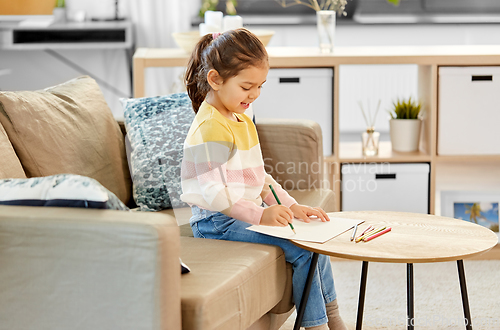 Image of little girl drawing with coloring pencils at home