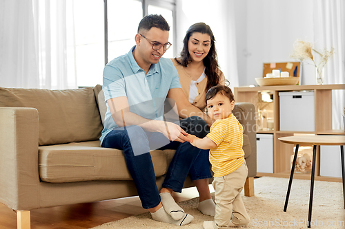 Image of happy family with child sitting on sofa at home