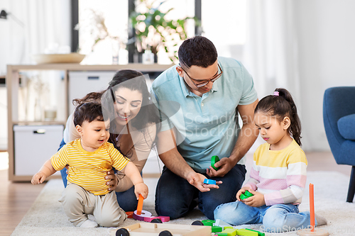 Image of happy family palying with wooden toys at home