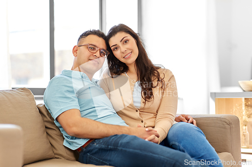 Image of happy couple sitting on sofa at home