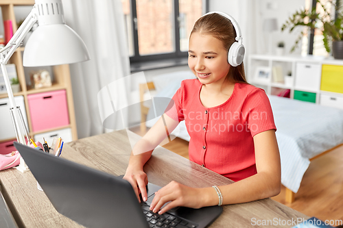 Image of girl in headphones with laptop computer at home