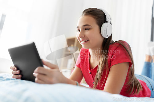 Image of girl in headphones listening to music on tablet pc
