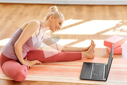 Image of woman with laptop exercising at yoga studio