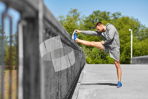 Image of man stretching leg on bridge