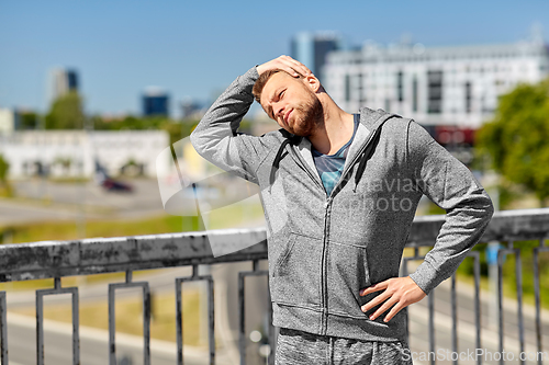 Image of man stretching neck on bridge