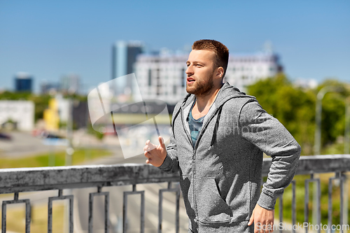 Image of happy young man running across city bridge