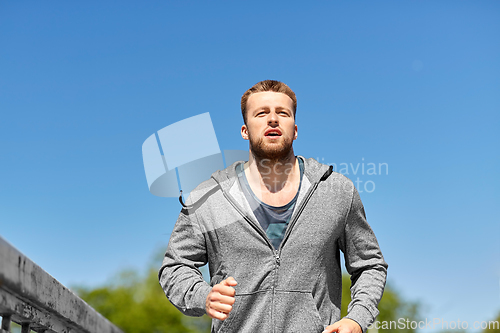 Image of happy young man running across city bridge