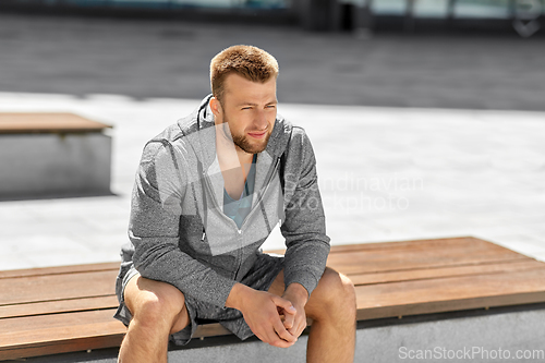 Image of young man sitting on bench outdoors