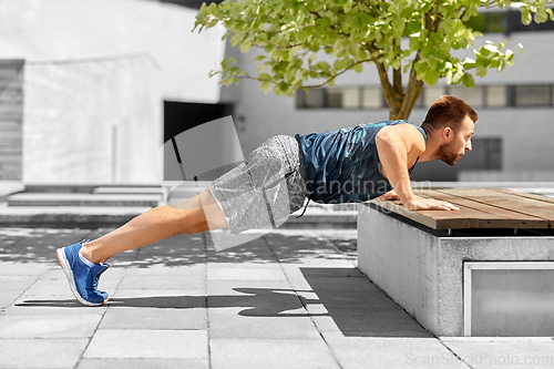 Image of young man doing push ups on city street