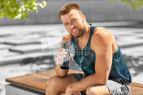 Image of sportsman with earphones and bottle in city