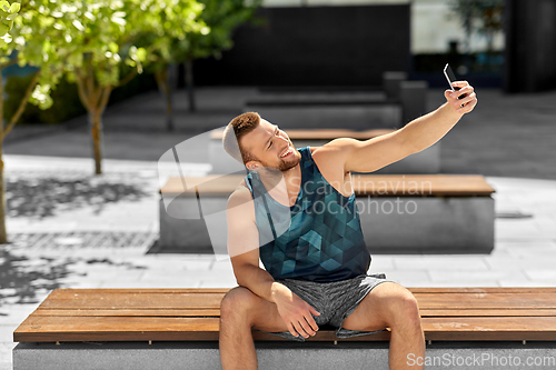 Image of man taking selfie with smartphone outdoors