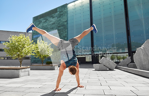 Image of young man exercising and doing handstand outdoors