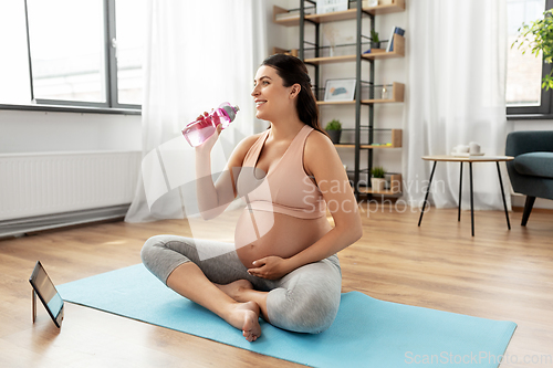 Image of pregnant woman drinking water after yoga at home