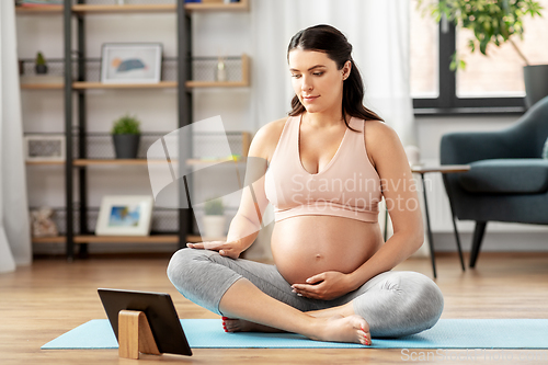 Image of pregnant woman with tablet pc doing sports at home