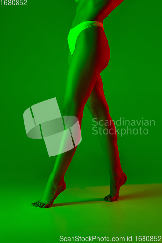 Image of Beautiful female legs on green background in neon light. Beauty, cosmetics, spa, depilation, diet and treatment, fitness concept.