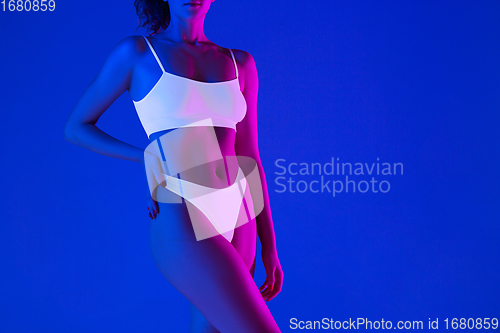 Image of Beautiful female body on blue background in neon light. Beauty, cosmetics, spa, depilation, diet and treatment, fitness concept.