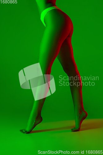 Image of Beautiful female legs on green background in neon light. Beauty, cosmetics, spa, depilation, diet and treatment, fitness concept.