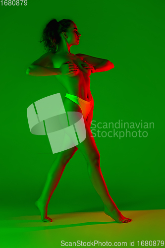 Image of Beautiful female body on green background in neon light. Beauty, cosmetics, spa, depilation, diet and treatment, fitness concept.