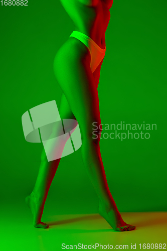 Image of Beautiful female legs on green background in neon light. Beauty, cosmetics, spa, depilation, diet and treatment, fitness concept.