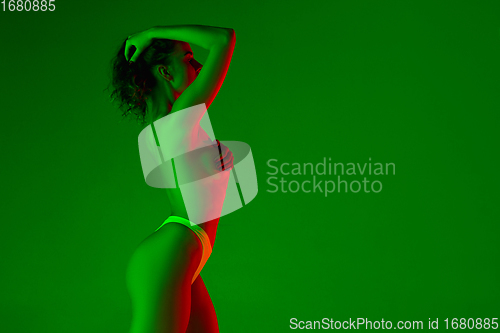 Image of Beautiful female body on green background in neon light. Beauty, cosmetics, spa, depilation, diet and treatment, fitness concept.