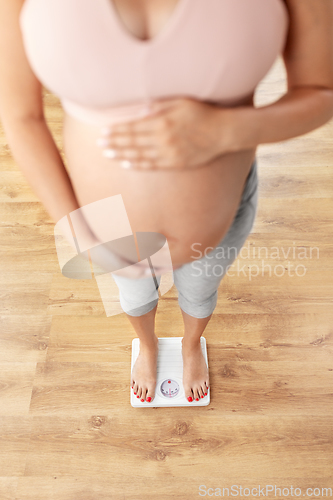 Image of pregnant woman standing on scales at home