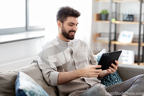 Image of smiling man with tablet computer at home
