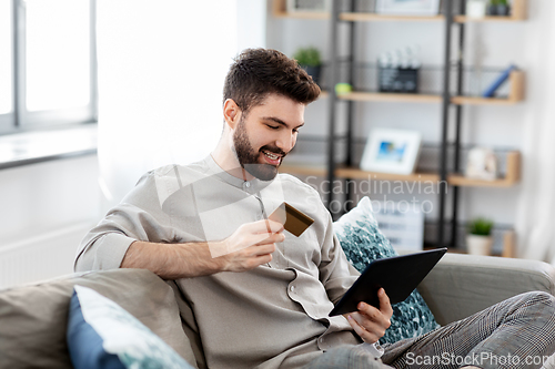 Image of man with tablet computer and credit card at home